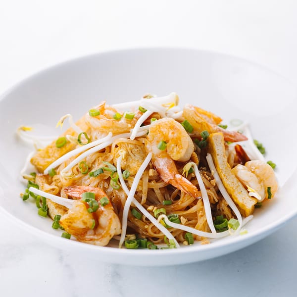 A white bowl of Asian Mint's Pad Thai with shrimp, bean sprouts, and green onions.