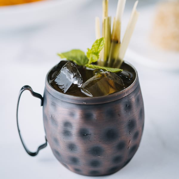 A Thai iced tea in a hammered copper mug with ice, mint, and lemongrass.