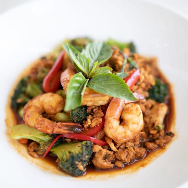 A Thai dish with shrimp, ground meat, broccoli, red peppers, and basil in a rich sauce.