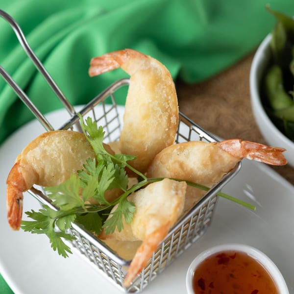 Crispy fried shrimp in a metal basket with cilantro, served with sweet chili sauce.