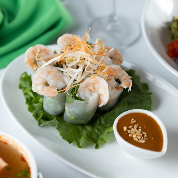 Fresh Thai spring rolls with shrimp, lettuce, and noodles, served with peanut sauce.