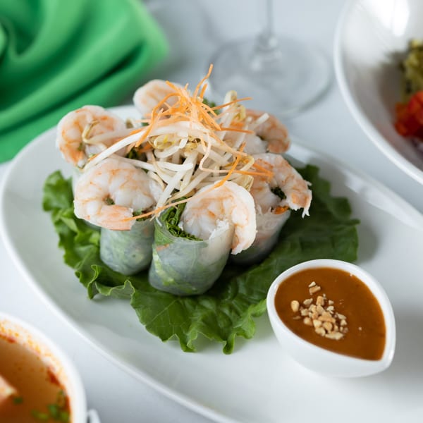 Thai shrimp spring rolls with bean sprouts, carrots, and lettuce, served with peanut sauce.