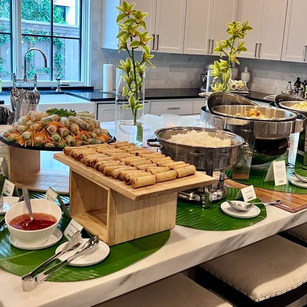 A Thai buffet spread with spring rolls, fried rolls, rice, and curry in a modern kitchen.
