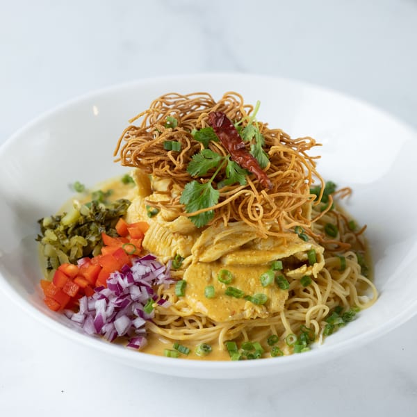 Asian Mint's Khao Soi with chicken, crispy noodles, red onion, bell pepper, and pickled greens.