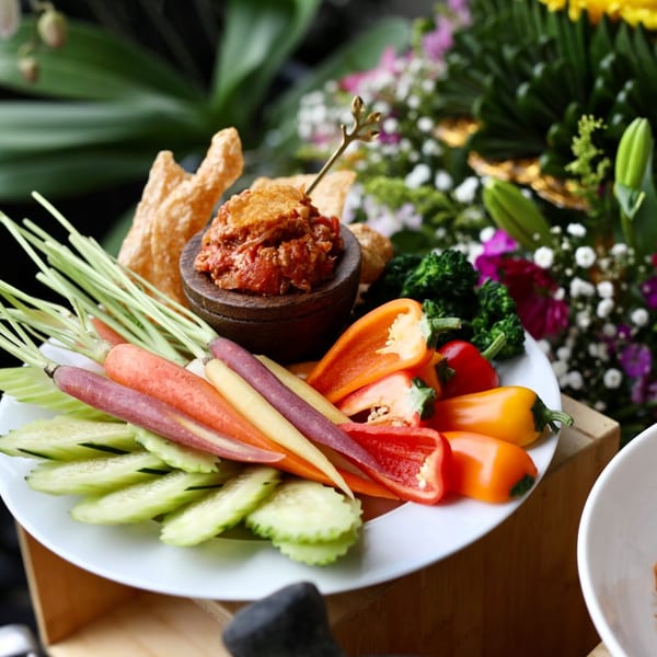 Colorful Thai appetizer platter with dip, fresh vegetables, and crispy chips.