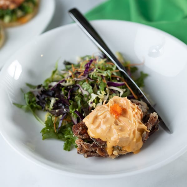 Crispy soft-shell crab with creamy orange sauce and orange roe, alongside a fresh green salad.