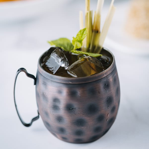 Iced Thai drink in a hammered copper mug, garnished with mint and lemongrass.