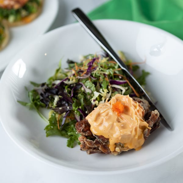 Crispy soft-shell crab with creamy sauce and orange roe, served with a fresh green salad.