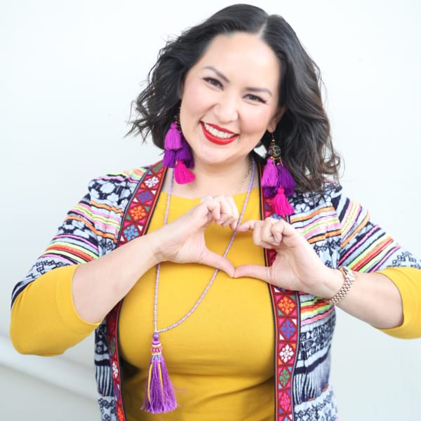 Asian Mint owner, smiling and making a heart shape with her hands.